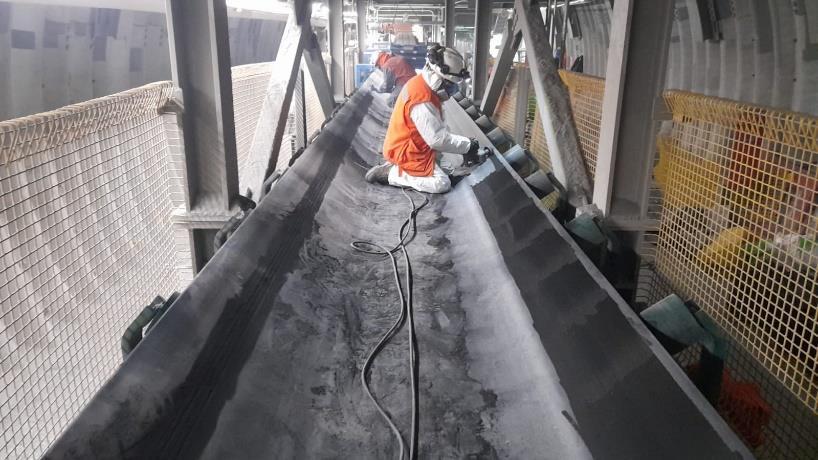 Técnico de VPS aplica polímero de reparación en el costado de una correa transportadora.
