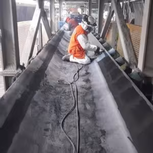 Técnico de VPS aplica polímero de reparación en el costado de una correa transportadora.