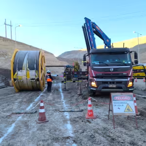 Camión grúa y rollos de cinta preparados para el cambio de una correa transportadora en faena.