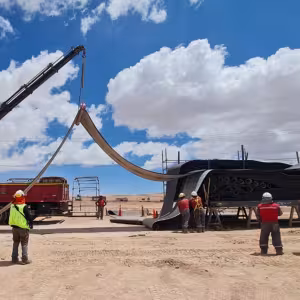 Grúa eleva una sección de cinta transportadora plegada durante los preparativos de montaje en faena.